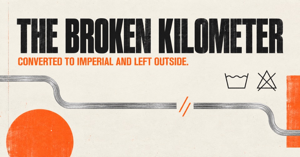 Campaign poster reading ‘The Broken Kilometer—converted to imperial and left outside,’ with a broken silver line and orange circle.